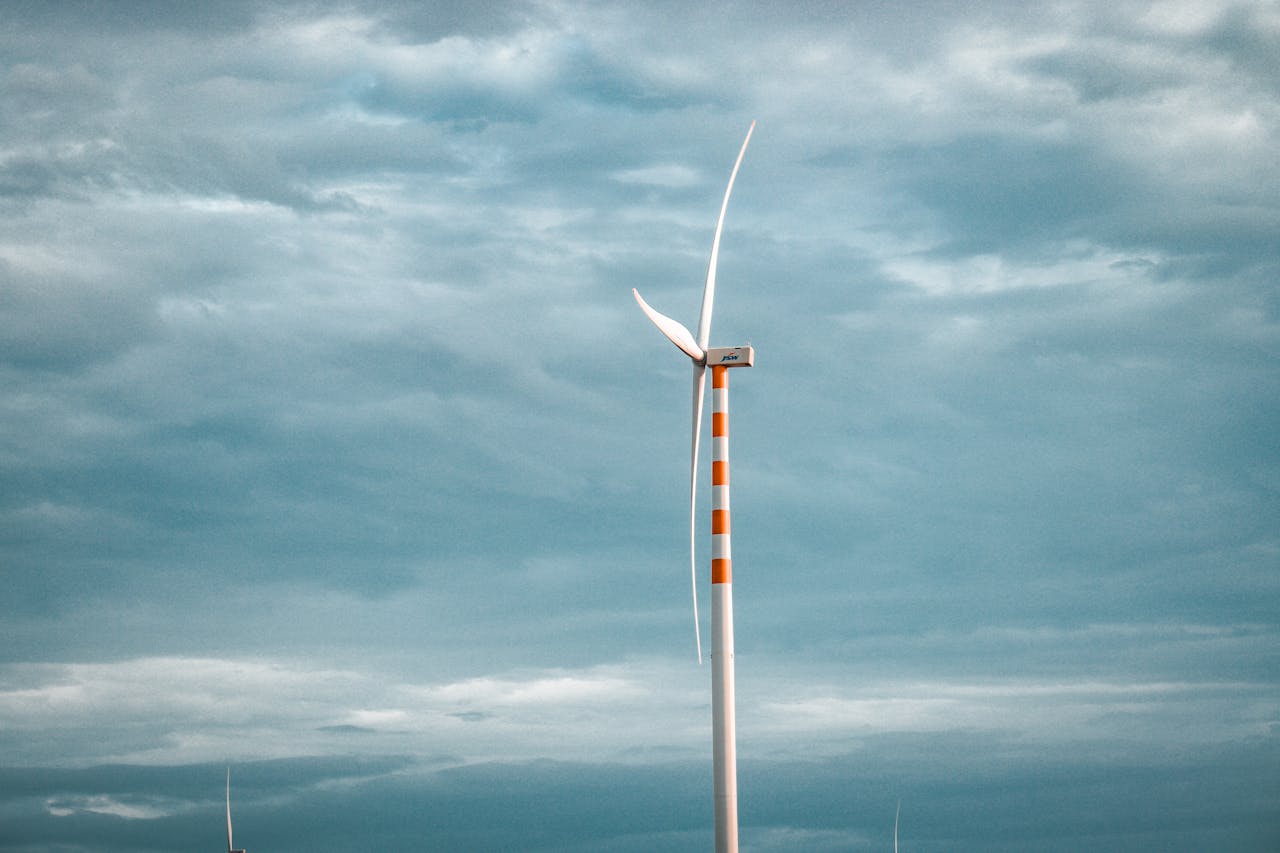 A single wind turbine stands tall against a backdrop of cloudy skies, symbolizing renewable energy.